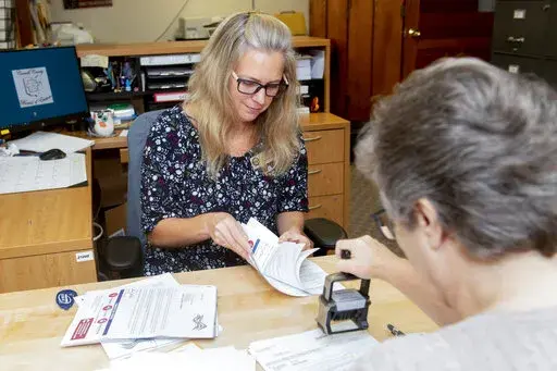 Carroll County Board of Elections Clerk Sarah Dyck, foreground, stamps incoming absentee ballot applications as Elections Clerk Deloris Kean counts more applications at the Board of Elections offices in Carrollton, Ohio, Sept. 26, 2022. (AP Photo/Phil Long)