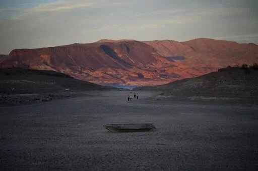 A formally sunken boat sits on cracked earth hundreds of feet from what is now the shoreline on Lake Mead at the Lake Mead National Recreation Area, Monday, May 9, 2022, near Boulder City, Nev. Lake Mead is receding and Sin City is awash with mob lore after a second set of human remains emerged within a week from the depths of the drought-stricken Colorado River reservoir just a short drive from the Las Vegas Strip.  (AP Photo/John Locher)