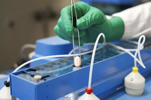 In this photo provided by Pfizer, a technician handles one of the company's COVID-19 Paxlovid pills. COVID-19 patients have two new treatment options that can be taken at home. But that convenience comes with a catch: The pills have to be taken as soon as possible once symptoms appear. U.S. regulators authorized the pills from Pfizer and Merck late 2021. (Pfizer via AP, File)