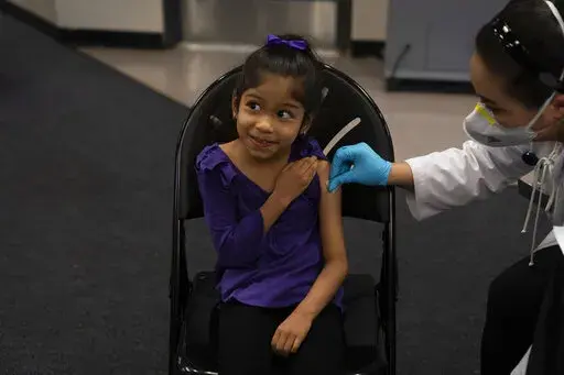 Elsa Estrada, 6, smiles at her mother as pharmacist Sylvia Uong applies an alcohol swab to her arm before administering the Pfizer COVID-19 vaccine at a pediatric vaccine clinic for children ages 5 to 11 set up at Willard Intermediate School in Santa Ana, Calif., Nov. 9, 2021. As of Tuesday, Jan. 11, 2022, just over 17% of children in the U.S. ages 5 to 11 were fully vaccinated, more than two months after shots for them became available. (AP Photo/Jae C. Hong, File)