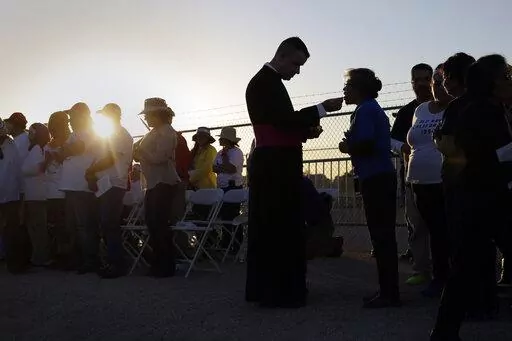 Migrants watching Pope Francis' Mass in Juarez, Mexico, from a levee along the banks of the Rio Grande in El Paso, Texas, take part in Communion, Wednesday, Feb. 17, 2016. According to a poll from The Associated Press-NORC Center for Public Affairs Research conducted in mid-May 2022, only 31% of lay Catholics agree that politicians supporting abortion rights should be denied Communion, while 66% say they be allowed access to the sacrament. (AP Photo/Eric Gay, File)
