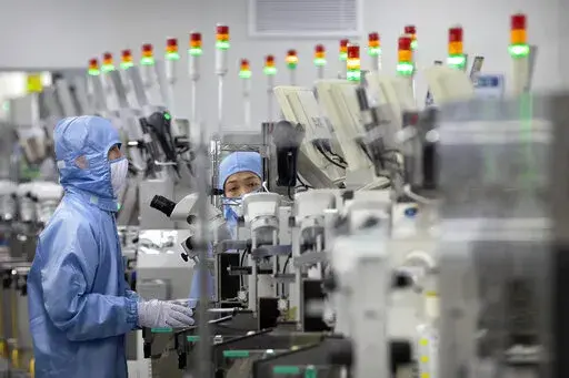 Employees wearing protective equipment work at a semiconductor production facility for Renesas Electronics during a government organized tour for journalists in Beijing, on May 14, 2020. House Democrats are poised to approve legislation Friday, Feb. 4, 2022, that they say positions the United States to better compete with China economically and on the global stage by strengthening the domestic semiconductor industry, shoring up strained supply chains and bolstering international alliances. (AP P