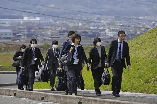 Japan's health ministry officials walk towards a plant operated by a subsidiary of Kobayashi Pharmaceutical Co. to conduct an on-site inspection in Kinokawa, south of Osaka, western Japan, Sunday, March 31, 2024. Japanese government health officials on Sunday inspected a factory producing health supplements linked to several deaths and the hospitalization of more than 100 others, one day after the authorities investigated another plant that manufactured the product. (Yohei Fukai/Kyodo News via A