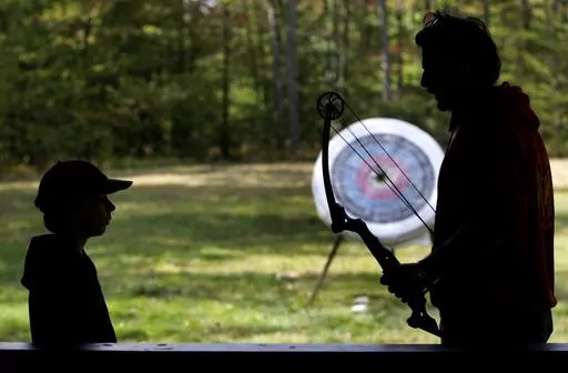 In this Oct. 3, 2009 photo, a Boy Scout, left, works with an instructor on the archery field at Boy Scout camp at Camp Minsi in Pocono Summit, Pa. While summer camp costs are rising, parents can find deals by booking sessions early, asking about financial aid, and leveraging sibling and other discounts. Sometimes, camps offer special deals on new programs or for certain age groups. Many nonprofits, service-based organizations and faith-based camps offer lower prices or even free sessions, and ch