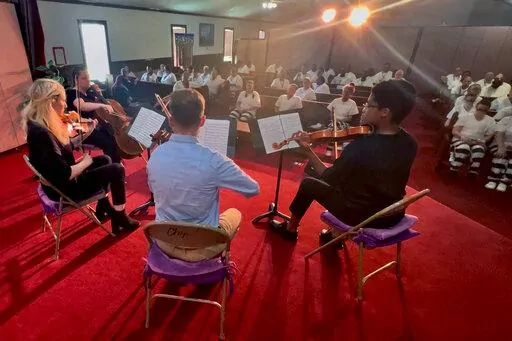 In this video frame grab provided by The Mississippi Department of Corrections, members of a string quartet of First Baptist Church of Jackson perform before inmates at the Central Mississippi Correctional Facility in Pearl, Miss., on Tuesday, July 19, 2022. The musicians included, from right, Noelani Perry, first violinist; Zakary Joyner, second violinist; Rebecca Franklin, viola; and Sarah Beth Mullen, cello. (Leo Honeycutt/The Mississippi Department of Corrections via AP)