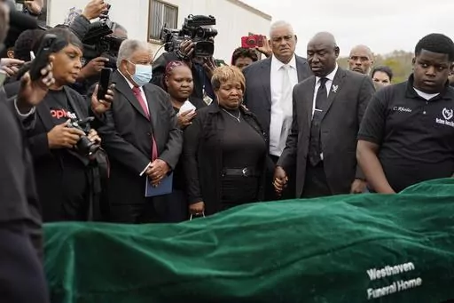 Civil rights attorney Ben Crump, center right, Bettersten Wade, center, mother of Dexter Wade, a 37-year-old man who died after being hit by a Jackson, Miss., police SUV driven by an off-duty officer, watches her son's body transferred to a mortuary transport after being exhumed from a pauper's cemetery near the Hinds County Penal Farm in Raymond, Monday, Nov. 13, 2023. After men in near Mississippi's capital were buried in a pauper’s cemetery without their relatives’ knowledge, the U.S. Jus