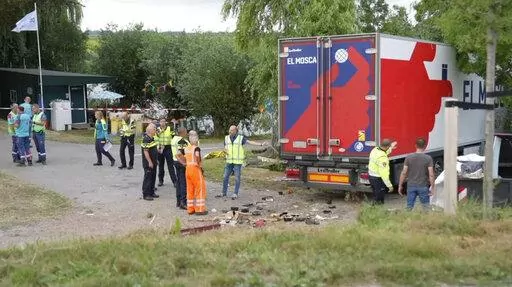In this frame grab taken from video, policemen and rescuers stand at the site where a truck plowed into a gathering in the village of Nieuw-Beijerland, Netherlands, Saturday Aug. 27, 2022. A truck drove off a dike and slammed into a community barbecue in a village south of Rotterdam on Saturday killing and injuring several people. (Media TV via AP)