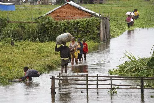 Residents wade through floodwater around their homes after heavy rain in Antananarivo, Madagascar, Jan. 19, 2022, killed at least 10 people. African officials outlined their priorities for the upcoming U.N. climate summit, including a push to make heavily polluting rich nations compensate poor countries for the environmental damage done to them. The continent will also focus on how countries can adapt to global warming and how the continent can best halt further climate-related disasters. (AP Ph