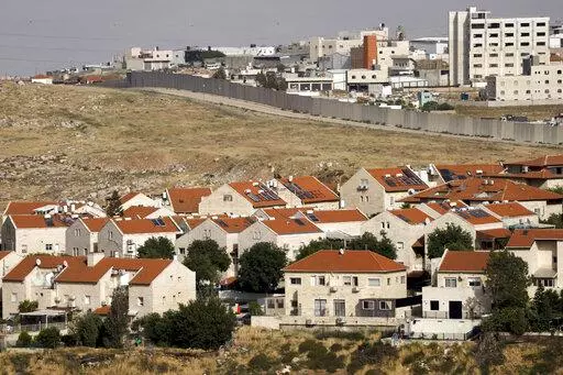 The east Jerusalem Israeli settlement of Pisgat Ze'ev, seen next to a section of the controversial separation barrier, Thursday, May 12, 2022. Israel advanced plans for the construction of more than 4,000 settler homes in the occupied West Bank on Thursday, a rights group said, a day after the military demolished homes in an area where hundreds of Palestinians face the threat of expulsion. (AP Photo/Maya Alleruzzo)
