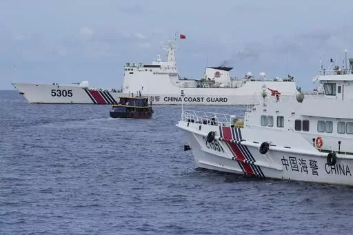 A Philippine supply boat, center, maneuvers around Chinese coast guard ships as they tried to block its way near Second Thomas Shoal, locally known as Ayungin Shoal, at the disputed South China Sea on Tuesday, Aug. 22, 2023. As a US Navy plane circled overhead, two Philippine navy-manned boats manage to breach through a Chinese coast guard blockade in a dangerous confrontation in the disputed South China Sea and succeeded in delivering food and other supplies to Filipino forces guarding a contes