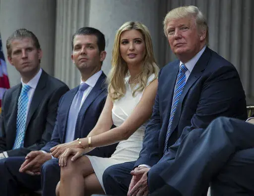 Donald Trump, right, sits with his children, from left, Eric Trump, Donald Trump Jr., and Ivanka Trump during a groundbreaking ceremony for the Trump International Hotel on July 23, 2014, in Washington. New York’s attorney general sued former President Donald Trump and his company on Wednesday, Sept. 21, 2022, alleging business fraud involving some of their most prized assets, including properties in Manhattan, Chicago and Washington, D.C. (AP Photo/Evan Vucci, File)