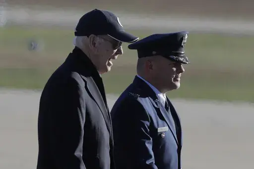 President Joe Biden, left, is escorted by Col. Paul Pawluk, Vice Commander, 89th Airlift Wing, right, as he walks from Marine One before boarding Air Force One at Joint Base Andrews, Md., Thursday, Oct. 17, 2024. (AP Photo/Luis M. Alvarez)
