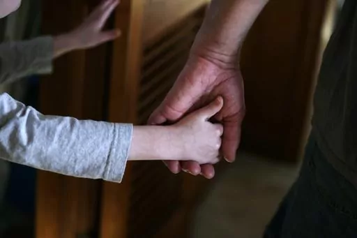An autistic boy holds the hand of his adoptive father as they prepare to leave for a family outing from their home in Springfield, Mass., on Saturday, Dec. 12, 2015. Traditionally, autism was diagnosed only in kids with severe language and social impairments and unusual repetitious behaviors. But the definition gradually expanded, and autism is now shorthand for a group of milder, related conditions, too. (AP Photo/Charles Krupa, File)