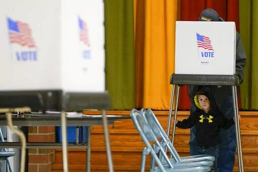 Jacob Lewis, 3, waits at a privacy booth as his grandfather, Robert Schroyer, fills out his ballot while voting at Sabillasville Elementary School, Nov. 8, 2022, in Sabillasville, Md. There were no digital intrusions known to have affected the counting of the U.S. midterm vote Wednesday after a tense Election Day in which officials were closely monitoring domestic and foreign threats. (AP Photo/Julio Cortez, File)