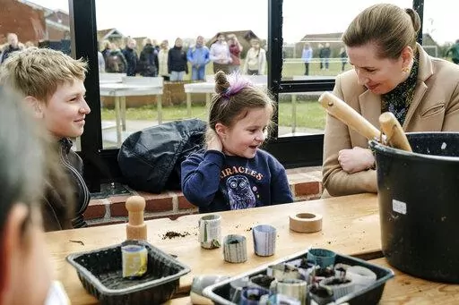 Danish Prime Minister Mette Frederiksen, right, meets Ukrainian refugee children at Paradisbakken school in Nexoe, as she visits the island of Bornholm in Denmark, Thursday, April 7, 2022. Anna Prokopiuk, center,  is from Ukraine but has lived in Denmark for three years and is therefore able to help interpret for the newly arrived refugees. (Pelle Rink/Ritzau Scanpix via AP)