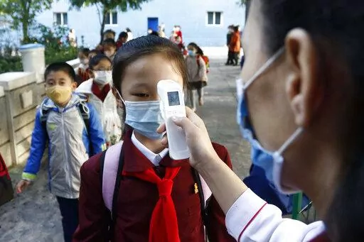 A teacher takes the body temperature of a schoolgirl to help curb the spread of the coronavirus before entering Kim Song Ju Primary School in Central District in Pyongyang, North Korea, on Oct. 13, 2021. On Saturday, July 30, 2022, North Korea reported no new fever cases for the first time since it abruptly admitted to its first domestic COVID-19 outbreak and placed its 26 million people under more draconian restrictions in May. (AP Photo/Cha Song Ho, File)