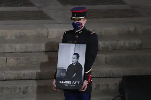A Republican Guard holds a portrait of Samuel Paty in the courtyard of the Sorbonne university during a national memorial event, Wednesday, Oct. 21, 2020 in Paris. (AP Photo/Francois Mori, Pool, File)