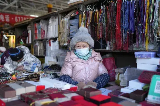 A senior woman waits for customers at a market in Beijing, Thursday, Jan. 16, 2025. (AP Photo/Aaron Favila)