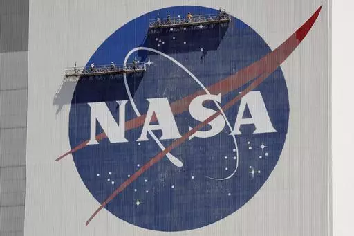 Workers on scaffolding repaint the NASA logo near the top of the Vehicle Assembly Building at the Kennedy Space Center in Cape Canaveral, Fla., May 20, 2020. (AP Photo/John Raoux, File)