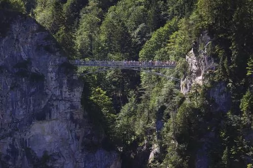 Tourists stand on the Marienbr'cke bridge, near the Neuschwanstein castle, in Schwangau, Germany, Thursday, June 15, 2023. Authorities say an American man has been arrested in Germany after allegedly assaulting two tourists he met near Neuschwanstein castle. The attack, which occurred on Wednesday, left one of the women dead. Police said Thursday that the 30-year-old man met the two women on a hiking path and lured them onto a trail. They said the man then “physically attacked” the younger w