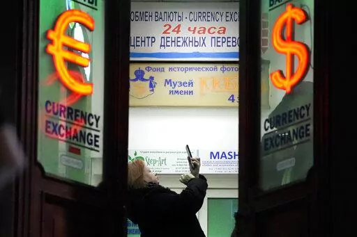 A woman stands in a currency exchange office in St. Petersburg, Russia, on Feb. 25, 2022. Russia plans to reopen its stock market for limited trading on Thursday, march 24, 2022, nearly one month after shares plunged and the exchange was shut down following the invasion of Ukraine. (AP Photo/File)