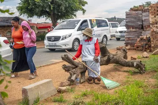 FILE - A woman watches hearses drive in convoy through Soweto, South Africa, Tuesday Dec. 7, 2021. Over 40 hearses took part in what was a COVID-19 vaccine awareness campaign, with the slogan: "We not in a hurry to see you!" From South African undertakers to ultra-Orthodox Israeli rabbis, an unconventional cadre of people has joined global efforts to increase COVID-19 vaccination rates. Launching campaigns that traditionally have been the realm of public health authorities, they’re opening chu