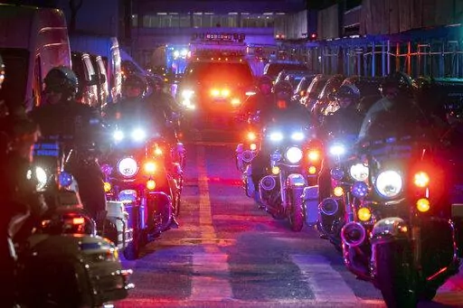 NYPD officers in motorcycles lead an ambulance carrying Officer Wilbert Mora as he is transferred from Harlem Hospital to NYU Langone hospital on Sunday, Jan. 23, 2022 in the Harlem neighborhood of New York. New York City Police Officer Jason Rivera was fatally shot Friday night while answering a call about an argument between a woman and her adult son. Mora and suspect Lashawn McNeil were wounded. (AP Photo/Yuki Iwamura)