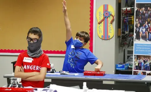 Aiden Trabucco, right, wears a mask as he raises his hand to answer a question behind Anthony Gonzales during a summer STEM camp at Wylie High School in Wylie, Texas, on July 14, 2020. Texas Gov. Greg Abbott’s executive order that forbids school districts from imposing mask mandates on schools to prevent the spread of COVID-19 was upheld Monday, July 25, 2022, by a divided federal appeals court panel in New Orleans. (AP Photo/LM Otero, File)