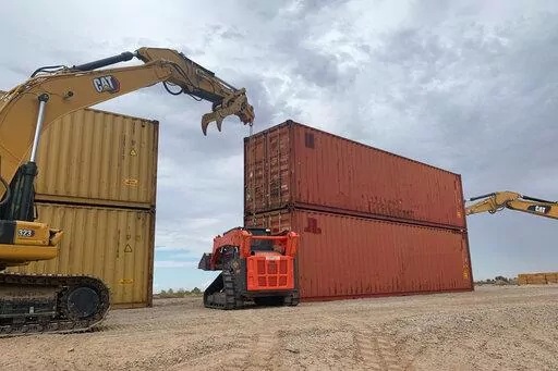 This photo provided by the Arizona Governor's Office shows shipping containers that will be used to fill a 1,000 foot gap in the border wall with Mexico near Yuma, Ariz., on Friday, Aug. 12, 2022. Two will be stacked atop each other and then topped with razor wire to slow migrants from crossing into Arizona. Republican Gov. Doug Ducey acted without federal permission and plans to fill three gaps totaling 3,000 feet in the coming weeks. (Arizona Governor's Office via AP)