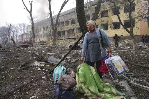 A woman walks outside a maternity hospital that was damaged by shelling in Mariupol, Ukraine, Wednesday, March 9, 2022. (AP Photo/Evgeniy Maloletka, File)