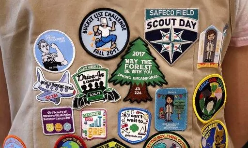 Patches cover the back of a Girl Scout's vest at a demonstration of some of their activities in Seattle, June 18, 2018. A federal judge, Thursday, April 7, 2022, tossed out a lawsuit in which the Girl Scouts claim that the Boy Scouts are creating marketplace confusion and damaging their recruitment efforts through their use of words such as "scouts" and "scouting." (AP Photo/Elaine Thompson, File)
