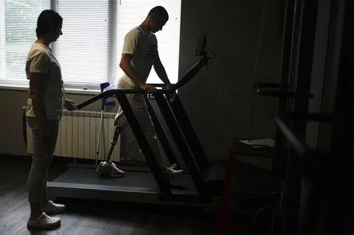 "Buffalo," the name he uses as a soldier, walks in a treadmill at a clinic in Kyiv, Ukraine, Friday, June 17, 2022. "Buffalo" was at the Azovstal plant, in an underground bunker-turned-medical station that provided shelter from death and destruction above. He was among those in the list for evacuation after being shredded by mortar rounds, losing his left leg above the knee. (AP Photo/Natacha Pisarenko)