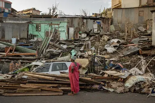 A woman looks at a destroyed home in Mamoudzou, Mayotte, Thursday, Dec. 19, 2024. (AP Photo/Adrienne Surprenant)