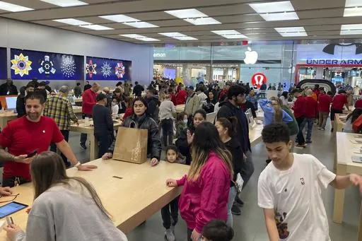 People shop at an Apple store in the Westfield Garden State Plaza mall in Paramus, New Jersey, on Saturday, December 17, 2022. On Friday, the Commerce Department issues its February report on consumer spending. (AP Photo/Ted Shaffrey, File)