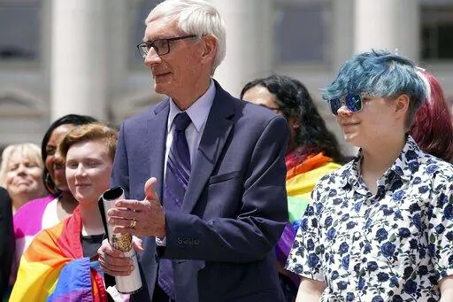 Wisconsin Gov. Tony Evers, left, stands next to 16-year-old Aspen Morris at the Rainbow Pride flag raising Wednesday, June 1, 2022 at the Capitol in Madison, Wis. Democratic political candidates who otherwise support the civil rights, safety and visibility of LGBTQ adults and children are finding it difficult to respond to a Republican vote-getting offensive targeting such people. The Republicans' use of LGBTQ people as a “wedge issue” seeks to appeal to the general public’s emotions and m