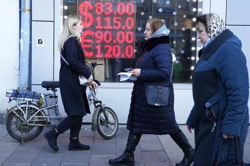 People walk past a currency exchange office screen displaying the exchange rates of U.S. Dollar and Euro to Russian Rubles in Moscow's downtown, Russia, Feb. 28, 2022. Nearly two months into the Russian-Ukraine war, the Kremlin has taken extraordinary steps to blunt an economic counteroffensive from the West. While Russia can claim some symbolic victories, the full impact of Western sanctions is starting to be felt in very real ways. (AP Photo/File)