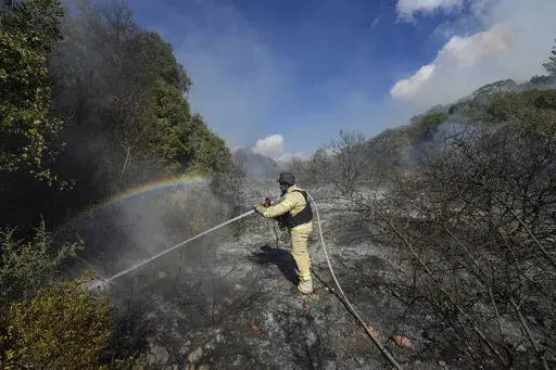 An Israeli firefighter works to extinguish a fire after a rocket fired from Lebanon hit an open field in northern Israel, Wednesday, Sept. 18, 2024. (AP Photo/Baz Ratner)