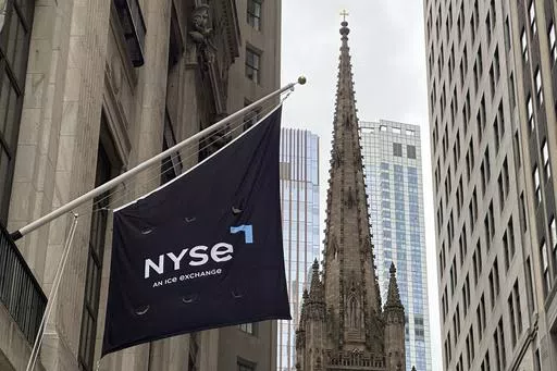 A flag hangs from the side of the New York Stock Exchange is on Thursday, May 16, 2024, in New York. Trinity Church appears in the background. (AP Photo/Peter Morgan, File)