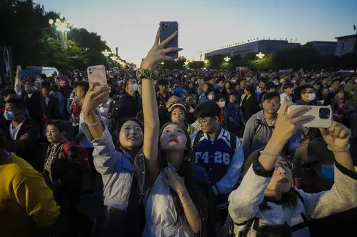 People take smartphone photos of the crowd on a street near Tiananmen Square as visitors gather to watch a flag-raising ceremony on the National Day in Beijing, Sunday, Oct. 1, 2023. The world’s population is expected to grow by more than 2 billion people in the next decades and peak in the 2080s at around 10.3 billion, a new report by the United Nations said Thursday July 11, 2024. (AP Photo/Andy Wong, File)
