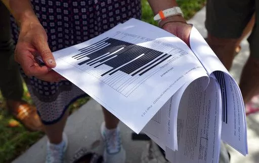 Journalists gather outside the Paul S. Rogers Federal Building and U.S. Courthouse in downtown West Palm Beach, Fla., to read a heavily blackout document released by The Justice Department Friday, Aug. 26, 2022.  The 32-page affidavit, even in its heavily redacted form, offers the most detailed description to date of the government records being stored at former President Donald Trump's Mar-a-Lago property long after he left the White House and reveals the gravity of the government's concerns th
