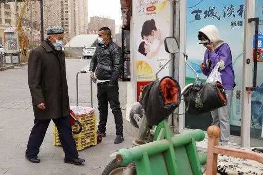 Residents wearing masks walk along the streets of Aksu in western China's Xinjiang region on Thursday, March 18, 2021. Residents of Ghulja, a city in China’s far west Xinjiang region say they are experiencing hunger, forced quarantines and dwindling supplies of medicine and daily necessities after more than 40 days in a virus lockdown. (AP Photo/Ng Han Guan, File)