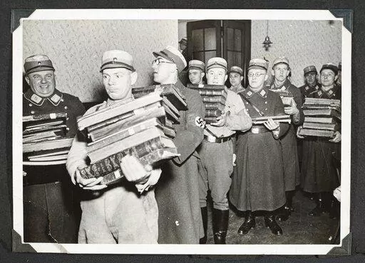 This photo released by Yad Vashem, World Holocaust Remembrance Center, shows German Nazis carry Jewish books, presumably for burning, during Kristallnacht intake most likely in the town of Fuerth, Germany on Nov. 10, 1938. The photos were taken by Nazi photographers during the pogrom in the city of Nuremberg and the nearby town of Fuerth. They wound up in the possession of a Jewish American serviceman who served in Germany during World War II. His descendants,donated the album to Yad Vashem. (Ya