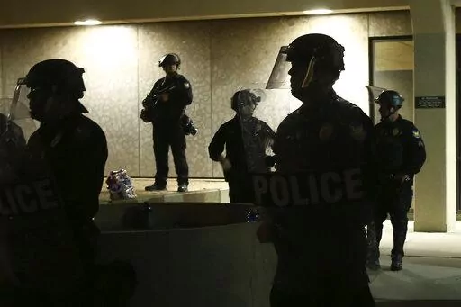 Phoenix Police stand in front of police headquarters on May 30, 2020, in Phoenix, waiting for protesters marching to protest the death of George Floyd. Arizona's governor has signed into law a measure that makes it illegal to knowingly record video of police officers within 8 feet (2.5 meters) or closer without an officer's permission, spurring concerns among civil rights activists about transparency and accountability. (AP Photo/Ross D. Franklin, File)