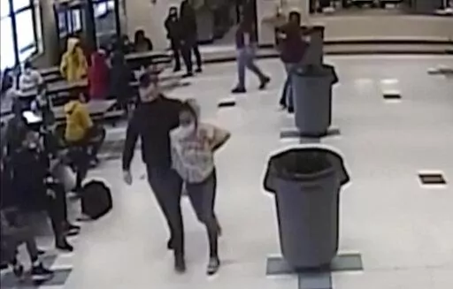 In this frame grab from surveillance video provided by the Kenosha Unified School District, an off-duty police officer escorts a 12-year-old student out of a school cafeteria following a lunchtime fight, in Kenosha, Wis., on March 4, 2022. Earlier in the video, the officer, who was working as a security guard, is shown intervening in the fight and putting his knee on the girl’s neck to restrain her. (Kenosha Unified School District via AP)
