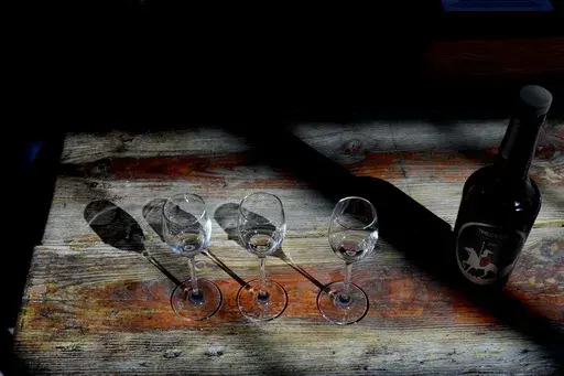 A bottle of Cyprus' famous Commandaria wine sits next to three glasses at the Karseras Winery in the mountain village of Doros on Friday, Feb. 21, 2025. (AP Photo/Petros Karadjias)