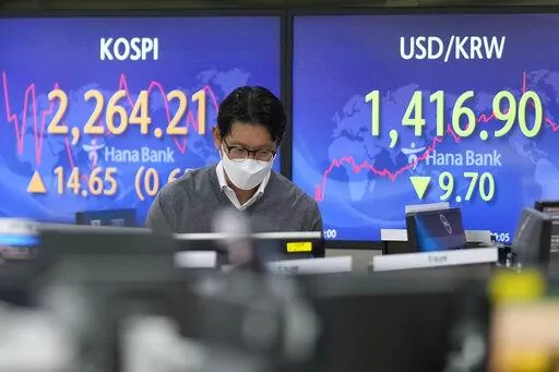 A currency trader walks by the screens showing the Korea Composite Stock Price Index (KOSPI), left, and the foreign exchange rate between U.S. dollar and South Korean won at a foreign exchange dealing room in Seoul, South Korea, Thursday, Oct. 27, 2022. Asian stock markets were mixed Thursday ahead of an update on the U.S. economy and a European Central Bank meeting that is expected to raise its key interest rate to a 13-year high. (AP Photo/Lee Jin-man)