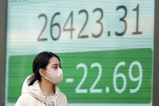 A person wearing a protective mask walks in front of an electronic stock board showing Japan's Nikkei 225 index at a securities firm Thursday, Jan. 12, 2023, in Tokyo. Asian shares were mixed Thursday ahead of a closely watched report on U.S. inflation viewed as a good indicator of whether Wall Street’s recent rising optimism is warranted or overdone. (AP Photo/Eugene Hoshiko)