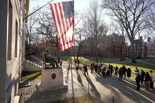People take photos near a John Harvard statue, left, on the Harvard University campus, Tuesday, Jan. 2, 2024, in Cambridge, Mass. On Wednesday, Jan. 10, several Jewish students filed a lawsuit against Harvard University, accusing it of becoming “a bastion of rampant anti-Jewish hatred and harassment.” (AP Photo/Steven Senne, File)