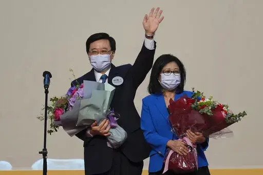 John Lee, former No. 2 official in Hong Kong and the only candidate for the city's top job, celebrates with his wife after declaring his victory in the chief executive election of Hong Kong in Hong Kong, Sunday, May 8, 2022. Lee was elected as Hong Kong's next leader Sunday by an election committee comprised of nearly 1,500 largely pro-Beijing members. (AP Photo/Kin Cheung)