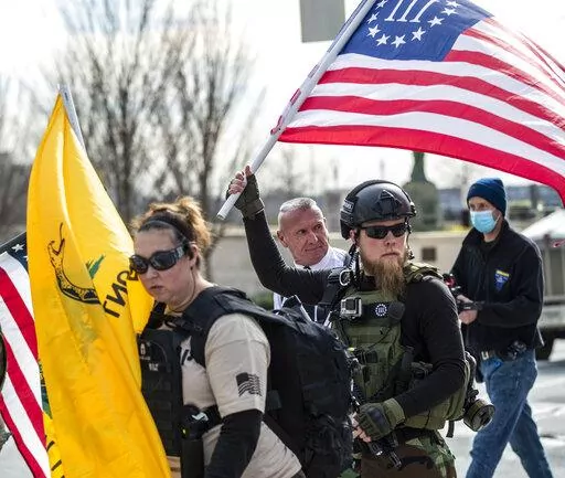 Chester Doles, rear center, leader of American Patriots USA, is surrounded by supporters as he makes his way to a 'Stop the Steal' rally outside of the Georgia State Capitol building, Wednesday, Jan. 6, 2021, in Atlanta. During the tumultuous period immediately following the November 2020 presidential election, election workers across the country faced harassment and threats. Since then, legislators in a small but growing number of states have proposed measures to help protect those workers by c